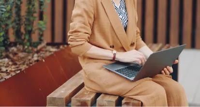 Woman working on a laptop on a garden bench